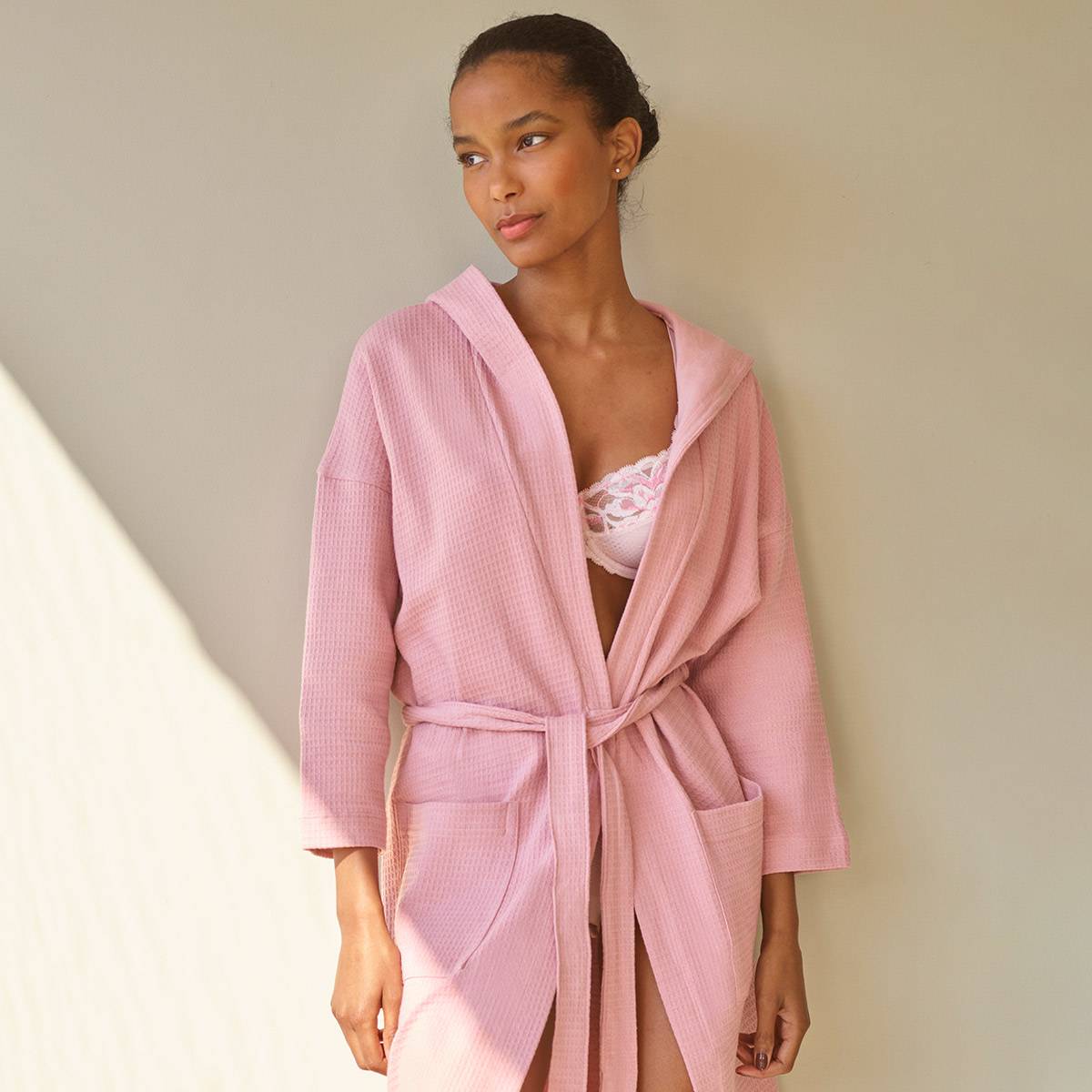 Woman wearing pink waffle-pattern dressing gown. Dressing gowns